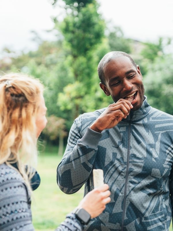 Friends eating a protein bar after a workout outside
