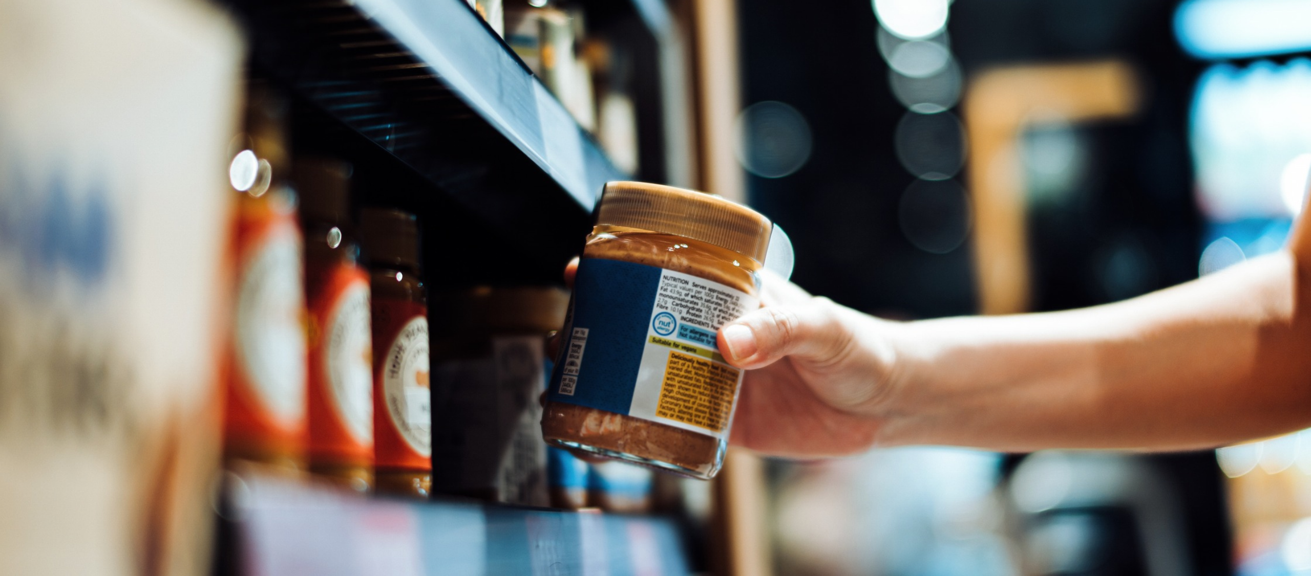 shopper grabbing a jar of peanut butter off the shelf